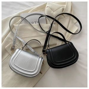 Detail of minimalist saddle bags in black and silver leather on a beige blazer