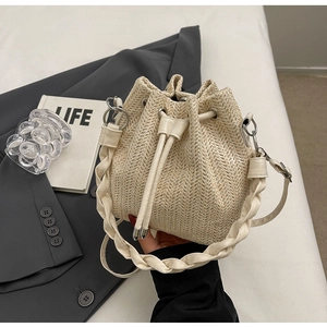 Detail of straw bucket bag with drawstring closure and woven leather handle texture