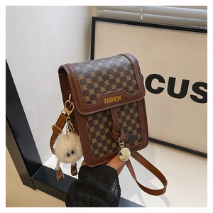 Détail d'un mini sac bandoulière marron vintage avec un pendentif en peluche blanc