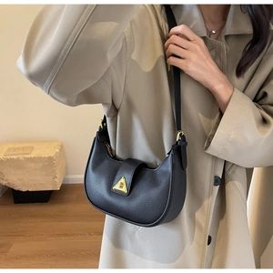 Détail du sac hobo en cuir grainé noir avec une boucle métallique triangulaire dorée