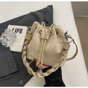 Detail of woven straw bucket bag with drawstring closure and mixed leather textures
