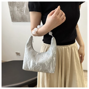 Detail of silver pleated shoulder bag featuring distinctive white marble bead chain strap