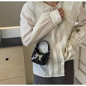 Détail d'un mini sac noir à paillettes avec boucle nœud argenté et bandoulière