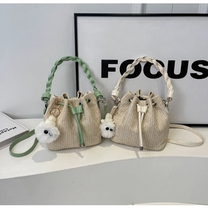 Detail of straw woven bucket bags with drawstring closure and cute plush pom charms