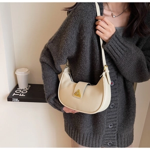 Détail macro du sac demi-lune beige crème avec grain litchi et boucle en métal doré