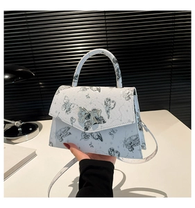 Détail du sac à main blanc avec imprimé papillon noir et fermoir nœud argenté