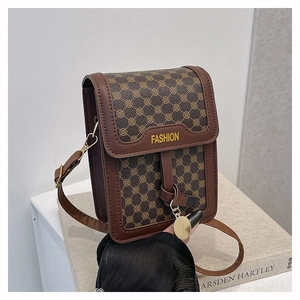 Gros plan du petit sac bandoulière vintage marron avec pendentif doré sur un livre