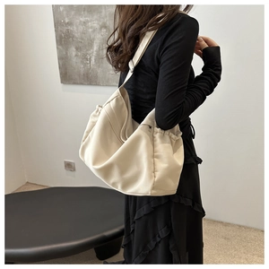 Detail of cream canvas hobo bag with drawstring sides and wide shoulder strap