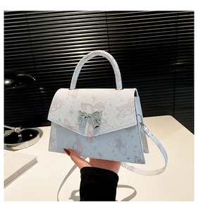 Détail du sac blanc à imprimé papillons avec fermoir en forme de nœud argenté élégant