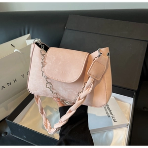 Detail of pink crossbody bag with flower chain strap and wide woven fabric shoulder strap