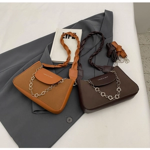 Close-up of braided handle and flower metal chain on vintage brown leather handbags