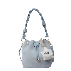 Light blue drawstring bucket bag with woven handle and plush charm on white background