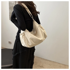 Detail view of large cream hobo bag showing side drawstring and premium texture