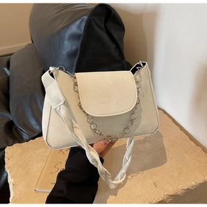 Detailed shot of cream PU leather bag featuring metal flower chain and branded logo