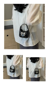 Détail d'un mini sac noir à paillettes avec nœud argenté et bandoulière chaîne sur modèle