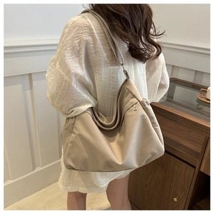 Detail of a large beige canvas hobo bag showing soft texture and silver zipper closure