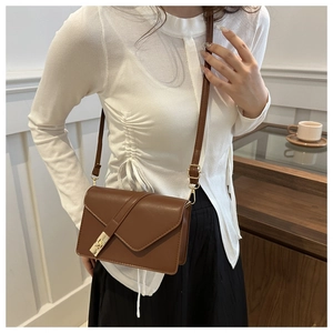 Close-up of brown vintage crossbody bag with gold buckle on a stylish model