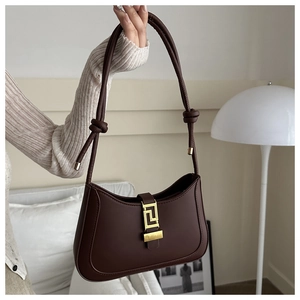 Détail du sac demi-lune marron foncé avec fermoir géométrique doré et bandoulière à nœuds