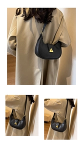 Détails d'un sac demi-lune en cuir noir grainé avec une boucle dorée triangulaire