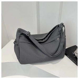 Detail view of large grey canvas tote bag showing side pleated pocket and adjustable strap