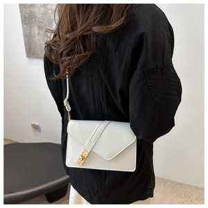 Close-up of minimalist white crossbody bag with gold metal buckle on a model
