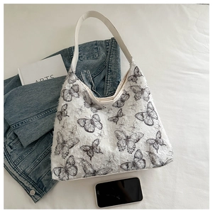 Detailed embroidery of black butterfly patterns on a white canvas shoulder tote bag