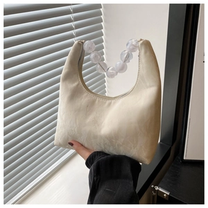 Detail of cream half-moon handbag featuring large acrylic bead handle and marble texture