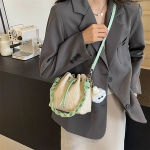 Straw woven bucket bag with drawstring and plush charm for beach vacations