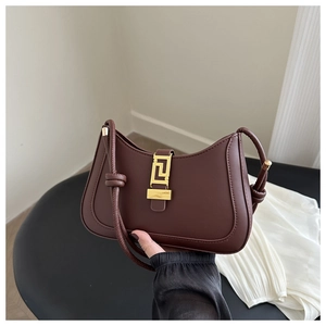 Detail of dark brown saddle bag with gold geometric Greek key lock and knotted strap