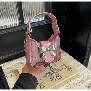 Détail d'un sac à main rose à paillettes avec un grand nœud argenté et chaîne