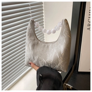 Detail of silver pleated fabric and marbled bead handle on a modern crescent bag