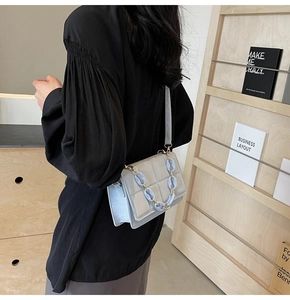 Detail view of light blue crossbody square bag with quilted pattern and decorative chain