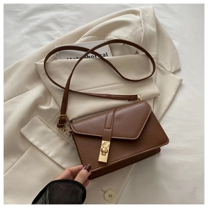 Detailed view of brown retro small square bag with golden turn-lock on a beige blazer