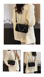 Detailed view of black pleated texture crossbody bag with elegant gold chain and strap