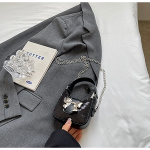 Détail du sac à main à paillettes noires avec boucle nœud argenté sur fond gris