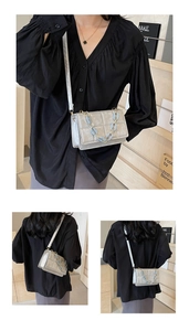 Detail of silver quilted crossbody bag with textured leather and decorative chain strap
