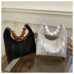 Detailed view of silver and black hobo bags featuring pleated texture and acrylic bead handles