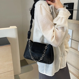 Minimalist black suede crossbody bag with decorative silver flower chain and wide strap