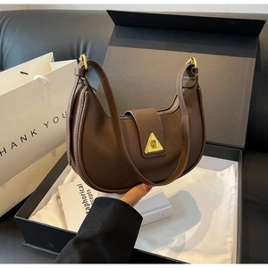 Détail d'un sac à main demi-lune en cuir marron avec boucle triangulaire dorée dans son coffret