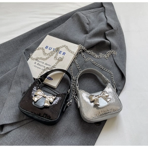 Détail de sacs bandoulière à paillettes avec nœuds métalliques et chaînes élégantes