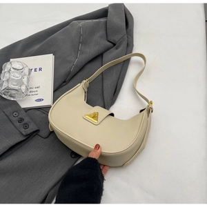 Détail du sac baguette en cuir grainé crème avec boucle dorée et rabat arrondi chic