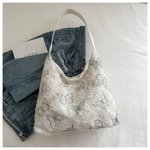Close-up of distressed lace butterfly print and frayed texture on the canvas shoulder bag