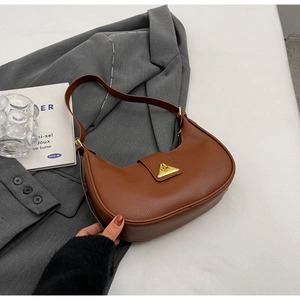 Détail d'un sac hobo marron avec fermoir triangle doré et texture cuir grainé