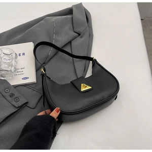 Détails de la texture cuir noir et du fermoir doré triangulaire sur un sac hobo chic