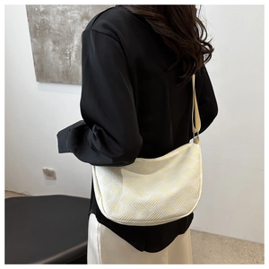 Close-up of beige woven hobo bag on shoulder featuring textured fabric and minimal design