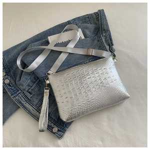 Detailed macro view of crocodile pattern silver envelope bag on a denim jacket