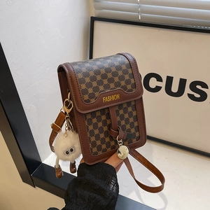 Close-up of brown patterned crossbody mini bag with FASHION logo and white fur ball charm