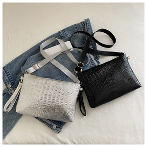 Detail of crocodile embossed crossbody bags in black and silver with wide straps