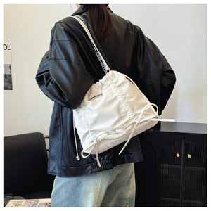 Weiße Kordelzug-Beuteltasche mit Schleife und Silberkette am Modell präsentiert