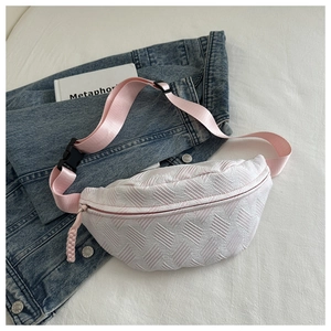 Detail of white woven textured chest bag with pink strap and black buckle on blue denim